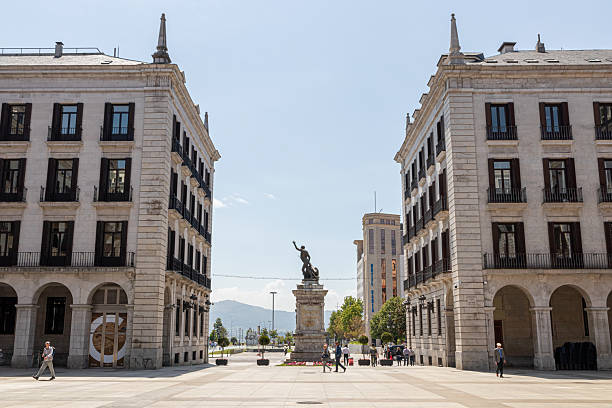 Santander, Spain. Full view of the bronze statue of Captain Pedro Velarde on a stone pedestal at the entrance to Plaza Porticada, with Neoclassical portico and surrounding arcaded buildings