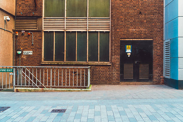 Industrial back alley in london with fire exit, electrical hazard sign, and security cameras