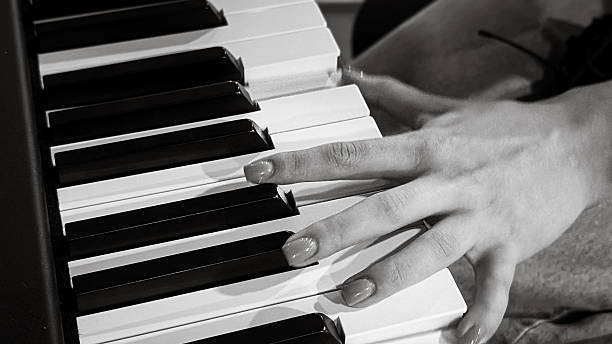 istock Female hand playing piano keys – black and white close-up 2228691123