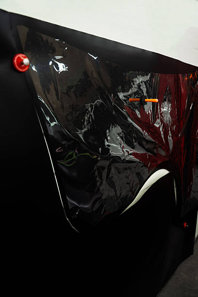 istock Vinyl wrap is manually cut using stencil over the film for precise shape replication. Vinyl film is trimmed using template directly placed on top. Manual Vinyl Wrap Cutting Using Physical Stencil. 2228691606