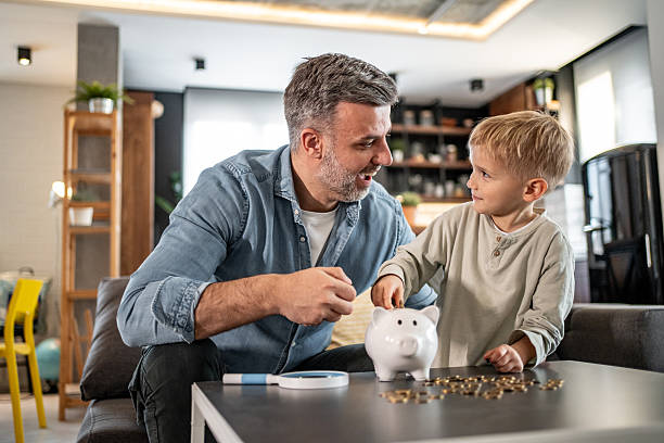 istock Father teaching son about saving money with piggy bank 2228692100