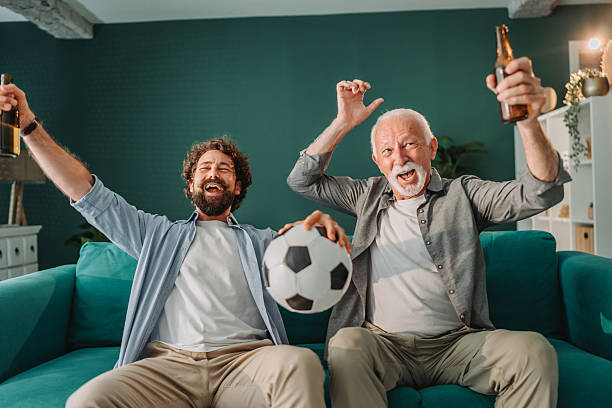 istock Father and son celebrating goal while watching soccer match at home 2228694119