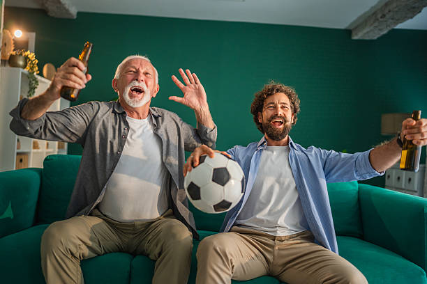 istock Father and son celebrating goal while watching soccer match at home 2228694149