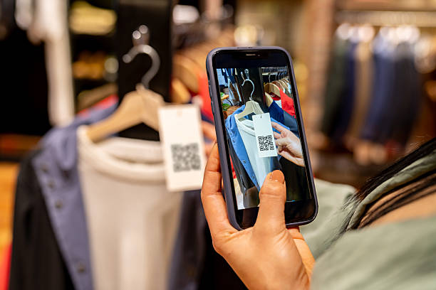 istock Customer at a clothing store scanning a tag using a cell phone 2228695421