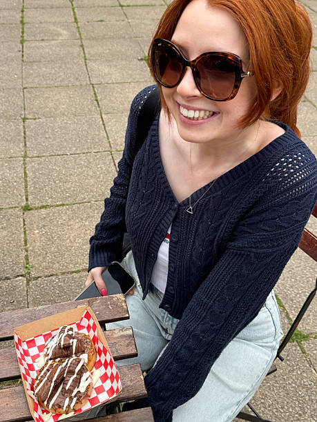 Image of girl eating breakfast with crumpets, melted chocolate, biscuits, donuts, doughnuts, sweet pudding dessert in takeaway box