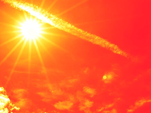 Bright sun with beautiful beams in the sky with some clouds. Toned in red color, space for copy.