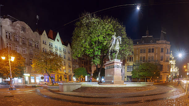 Equestrian statue of King Danylo illuminated at night in Lviv, Ukraine, with surrounding historic buildings