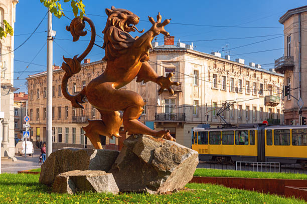 Bronze lion sculpture with passing yellow tram and old buildings in Lviv, Ukraine