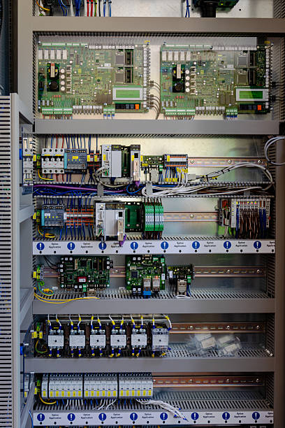 A close-up view of a modern electrical control panel featuring multiple circuit boards, relays, switches, wiring, and electronic components, inside a power distribution or industrial control room. The detailed arrangement of cables, controllers, and safety systems highlights advanced automation, engineering, and reliable energy management. The image is ideal for illustrating electrical infrastructure, power distribution, automation, and smart industry concepts in the energy sector