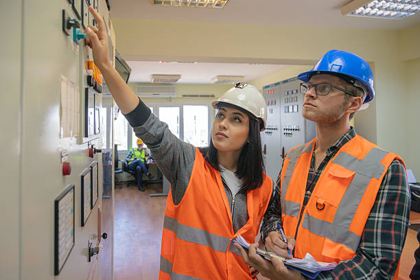 istock Young Female and Male Engineers Operating Electrical Control Panel in Modern Power Plant Control Room with Safety Helmets and High Visibility Vests 2228703269