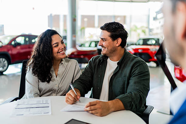 istock Couple signing documents at car dealership 2228705752