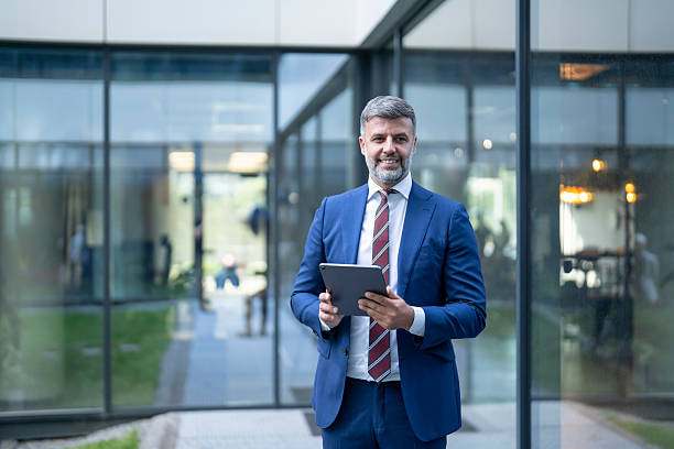 istock Smiling businessman holding digital tablet outside office building 2228713304
