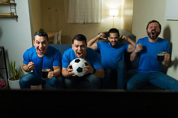 istock Four friends cheering while watching soccer match at home 2228715265