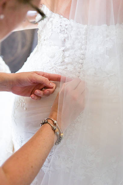 istock Hands fastening buttons on bride’s lace gown before ceremony 2228716029