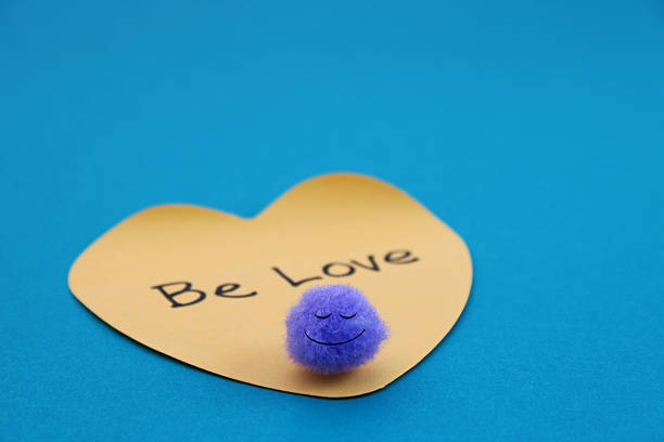 Happy face and sticky note with the phrase be love