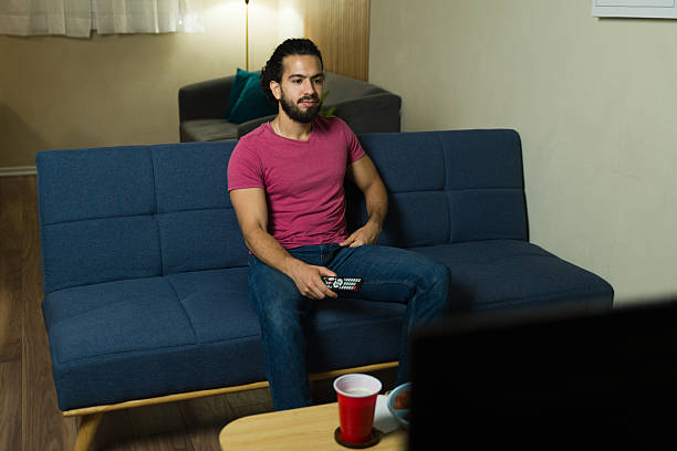 istock Young man watching tv and relaxing on sofa at home 2228717603