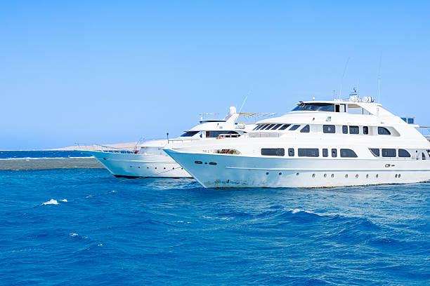 A sleek white luxury yacht sails across a tranquil blue ocean with a bright day sky, evoking leisure, travel, and premium boating lifestyle.