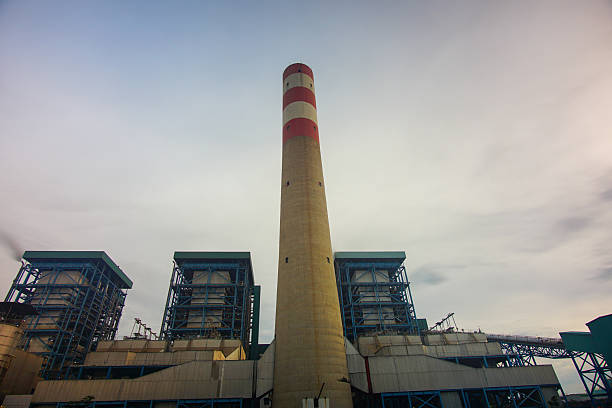 istock Industrial facility featuring a towering smokestack with distinct red and white stripes against a cloudy backdrop 2228720440