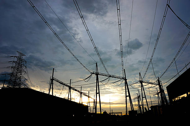 A dramatic silhouette of an electrical substation at twilight, with power lines stretching across a cloudy sky. The image evokes a sense of energy infrastructure, highlighting the network's crucial