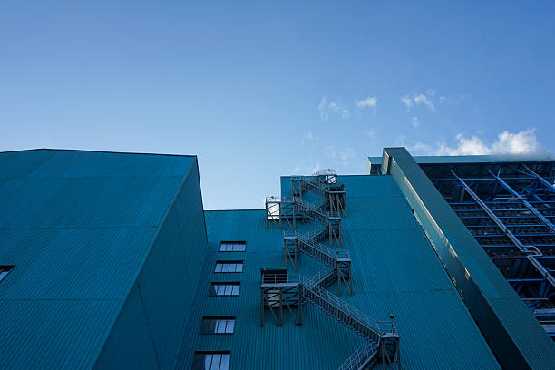 Stone steps leading to glass double doors of modern office building with blue glass facade reflecting the sky in london