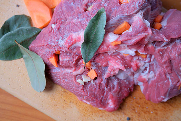 Brightly colored raw meat is garnished with carrots and herbs, ready to cook.