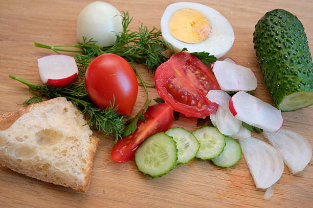 Colorful vegetables, herbs, and eggs neatly displayed on a wooden board.