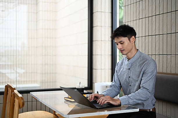 istock Asian businessman working on a laptop at a modern cafe table 2228727429