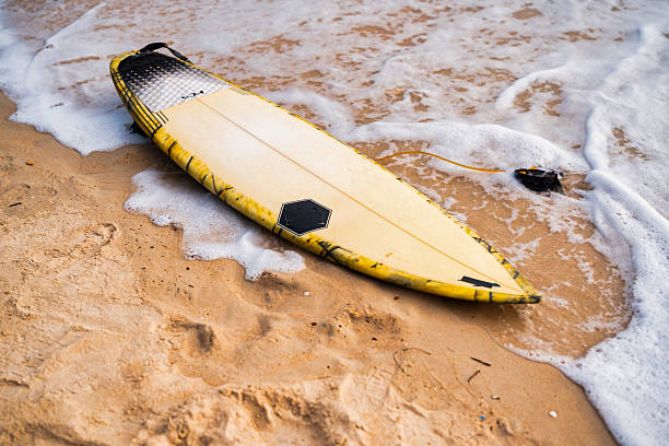 istock Surfboard resting on sandy beach near ocean waves at sunset 2228727750