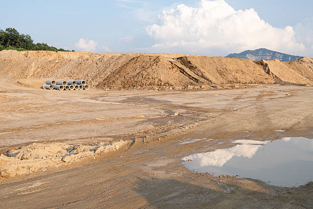 istock Expansive construction site with exposed earth and heavy machinery tracks. Surrounded by distant mountains, the scene captures early stages of land development and earthmoving operations. 2228728387