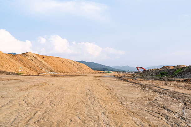 istock Expansive construction site with exposed earth and heavy machinery tracks. Surrounded by distant mountains, the scene captures early stages of land development and earthmoving operations. 2228728438