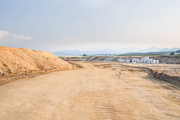 istock Expansive construction site with exposed earth and heavy machinery tracks. Surrounded by distant mountains, the scene captures early stages of land development and earthmoving operations. 2228728473