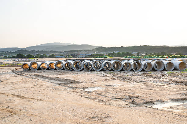 Expansive construction site with exposed earth and heavy machinery tracks. Surrounded by distant mountains, the scene captures early stages of land development and earthmoving operations.