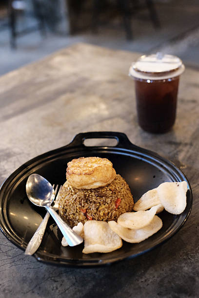 istock Savory Fried Rice Delight served with Crispy Crackers and Refreshing Tea Beverage on a Sleek Black Tray offering a culinary journey showcasing local flavors and visual treat ideal for food promotions 2228729356