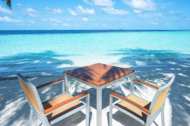 Empty table and chairs on the tropical beach by beautiful turquoise sea
