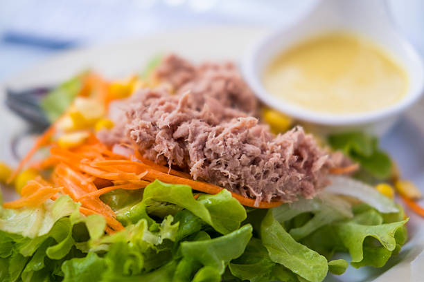 A close up shot of a healthy tuna salad sandwich in the process of being assembled. Shot on a wooden background.