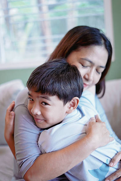 istock Son embraces his mother warmly on the sofa. 2228736619