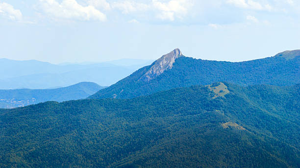 View of Jahorina mountain ridge with sharp rocky peak, surrounded by deep forest and layered horizon