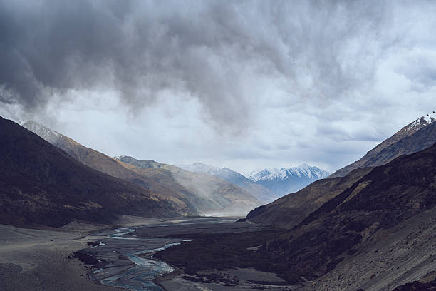istock Curving river through Himalayan valley in Ladakh under dramatic stormy sky with rugged mountains and snowy peaks 2228739639