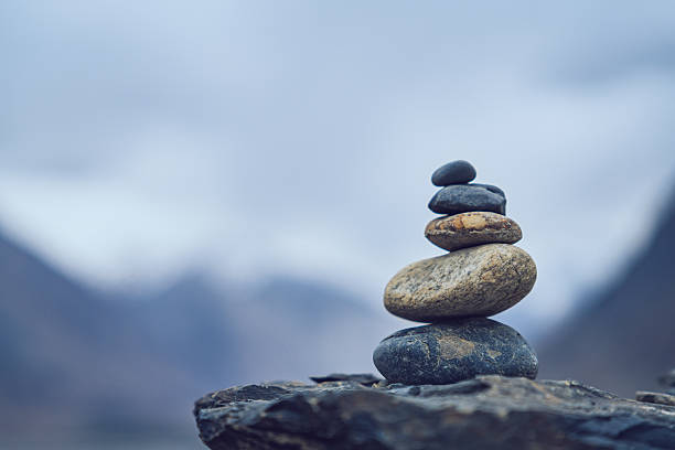 Minimalist stack of smooth stones in balance with blurred Himalayan mountain backdrop symbolizing serenity and mindfulness