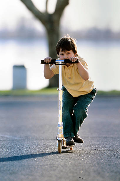 istock young boy riding a scooter in the square 2228740524