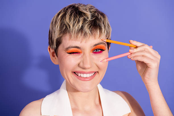 Smiling young woman with vibrant makeup posing creatively against a vibrant background with bright color accents