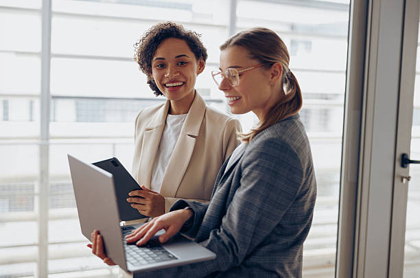 istock Group of female managers standing in modern office while working on laptop and digital tablet 2228745703