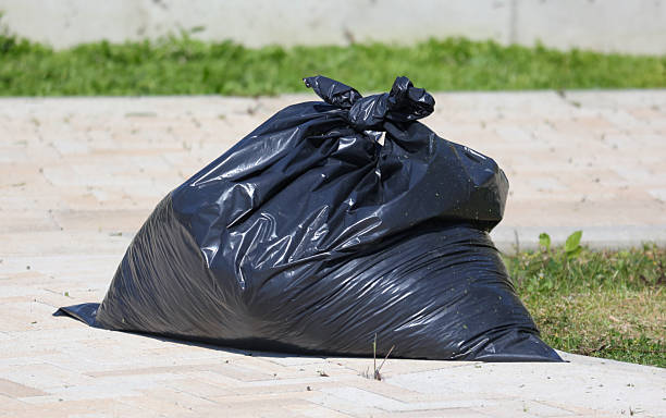 istock A black trash bag is sitting on the ground 2228747770