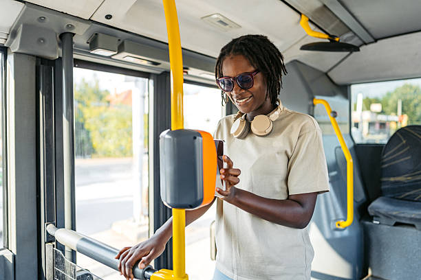 Beautiful young black woman checking her e-ticket with a phone in a public bus.