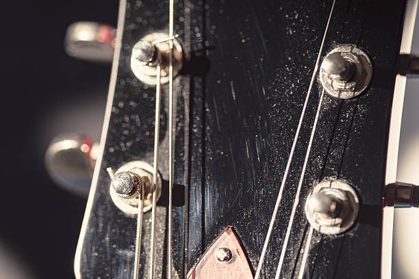 Guitar headstock showcasing intricate tuning pegs and strings. Textured surface and precise detailing emphasize craftsmanship and musical character