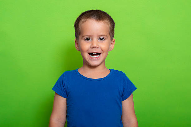 Happy little girl with short hair holding a rainbow painting. Smiling with her teeth. Over blue background.