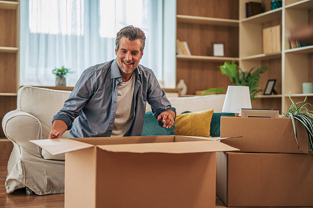istock Happy man unpacking cardboard boxes in new home 2228754210