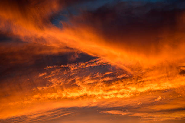 Dramatic cloudy sky illuminated orange from below by the setting or rising sun