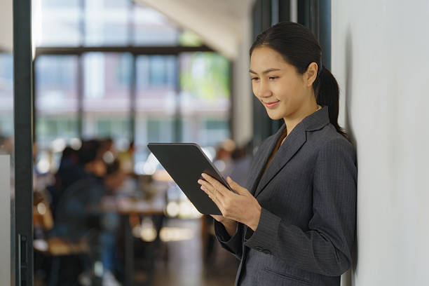 istock Smiling female office worker checking reports and using a digital tablet at the office. 2228754434