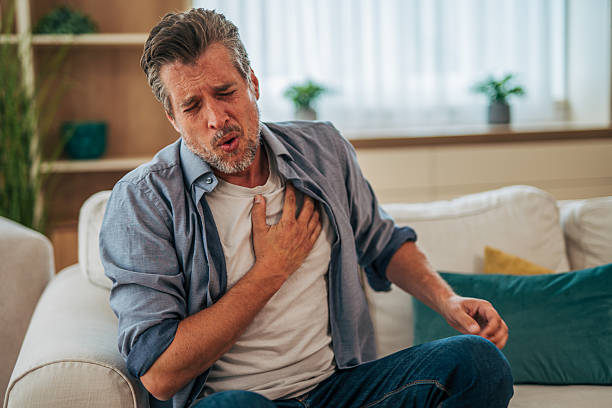 istock Mature man suffering chest pain while sitting on sofa at home 2228754664